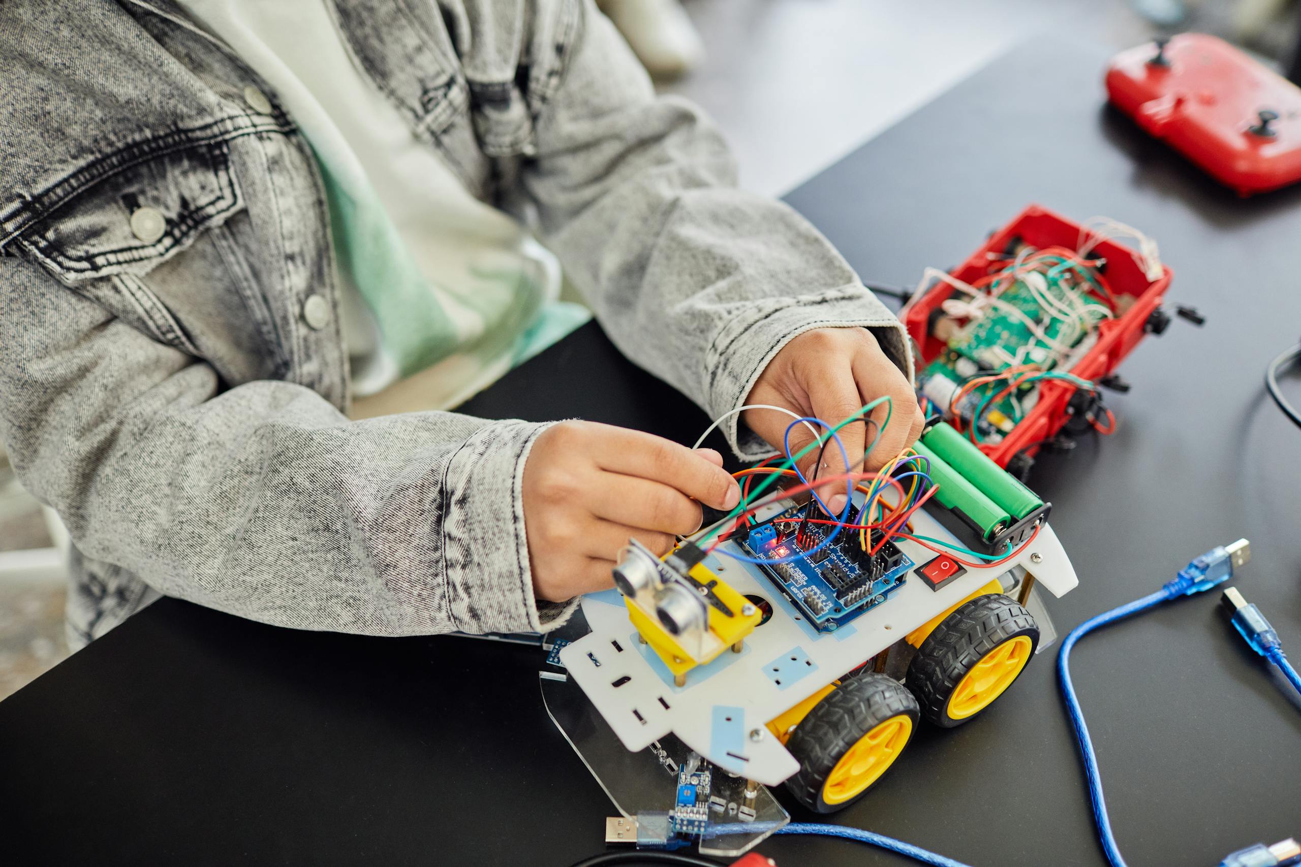 Young student assembling a toy car with electronic components, focusing on STEM education.